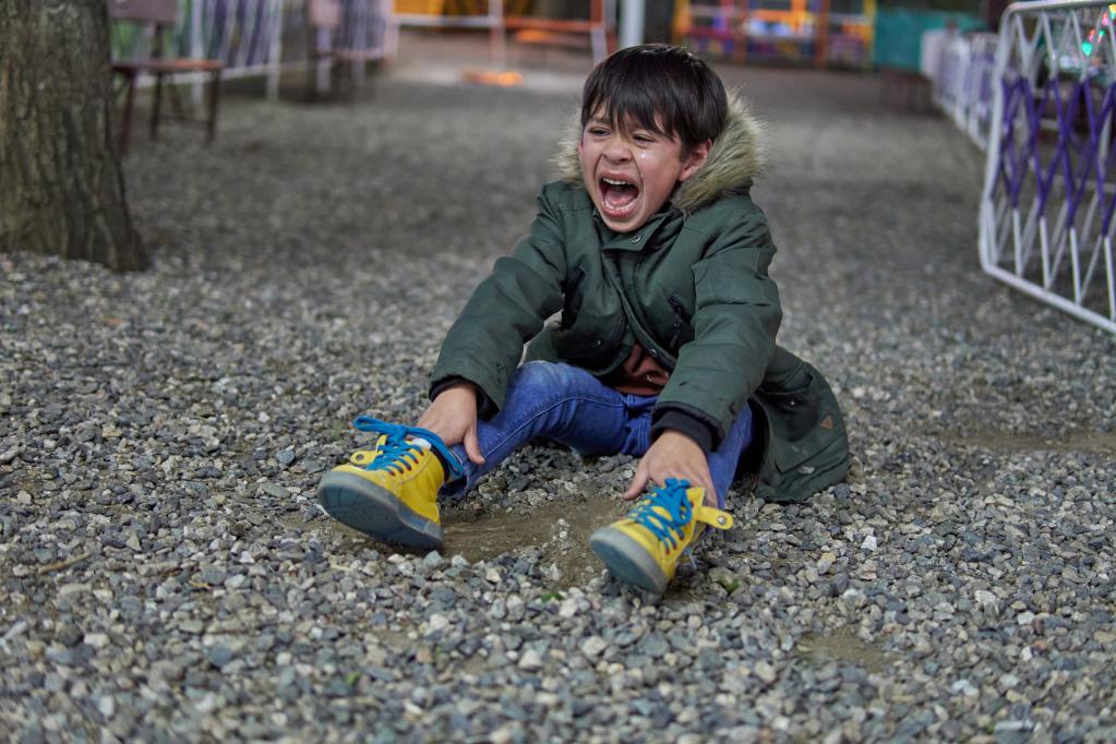 A photo of a child sitting on the ground having a tantrum