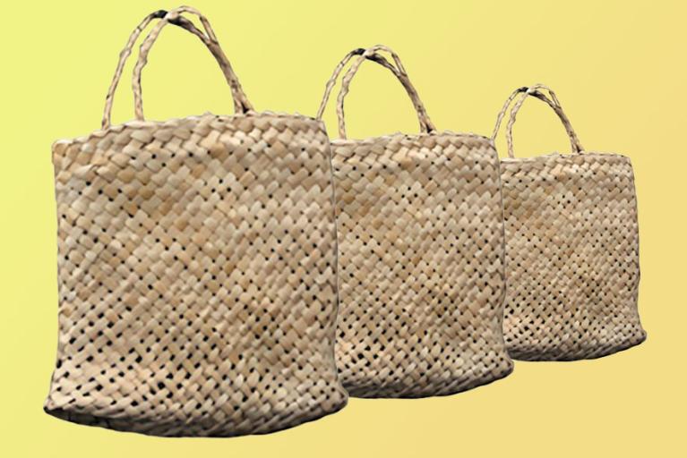 Three woven kete, traditional Māori flax baskets, arranged in descending size order against a yellow background.