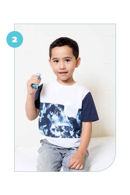 Photo of a child sitting holding an asthma inhaler