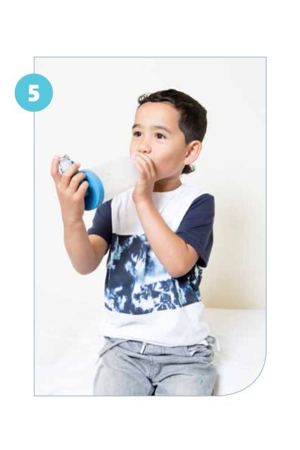 Photo of a child using an inhaler that is attached to a spacer