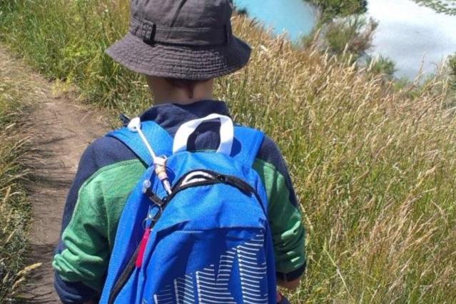 Alex carrying tube feeding equipment in his blue backpack while out walking