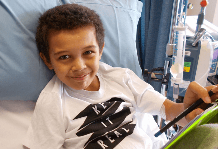 A boy in a hospital bed with a tablet