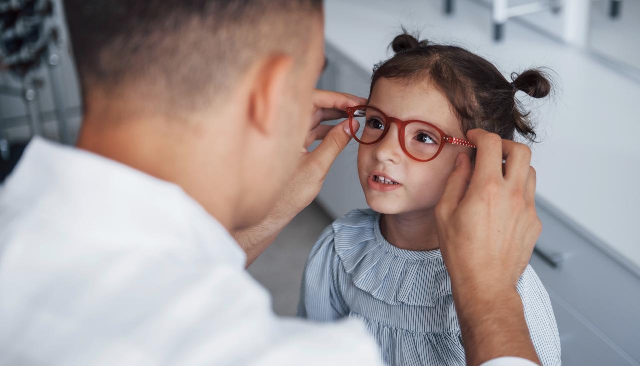 Optometrist fitting a child with glasses