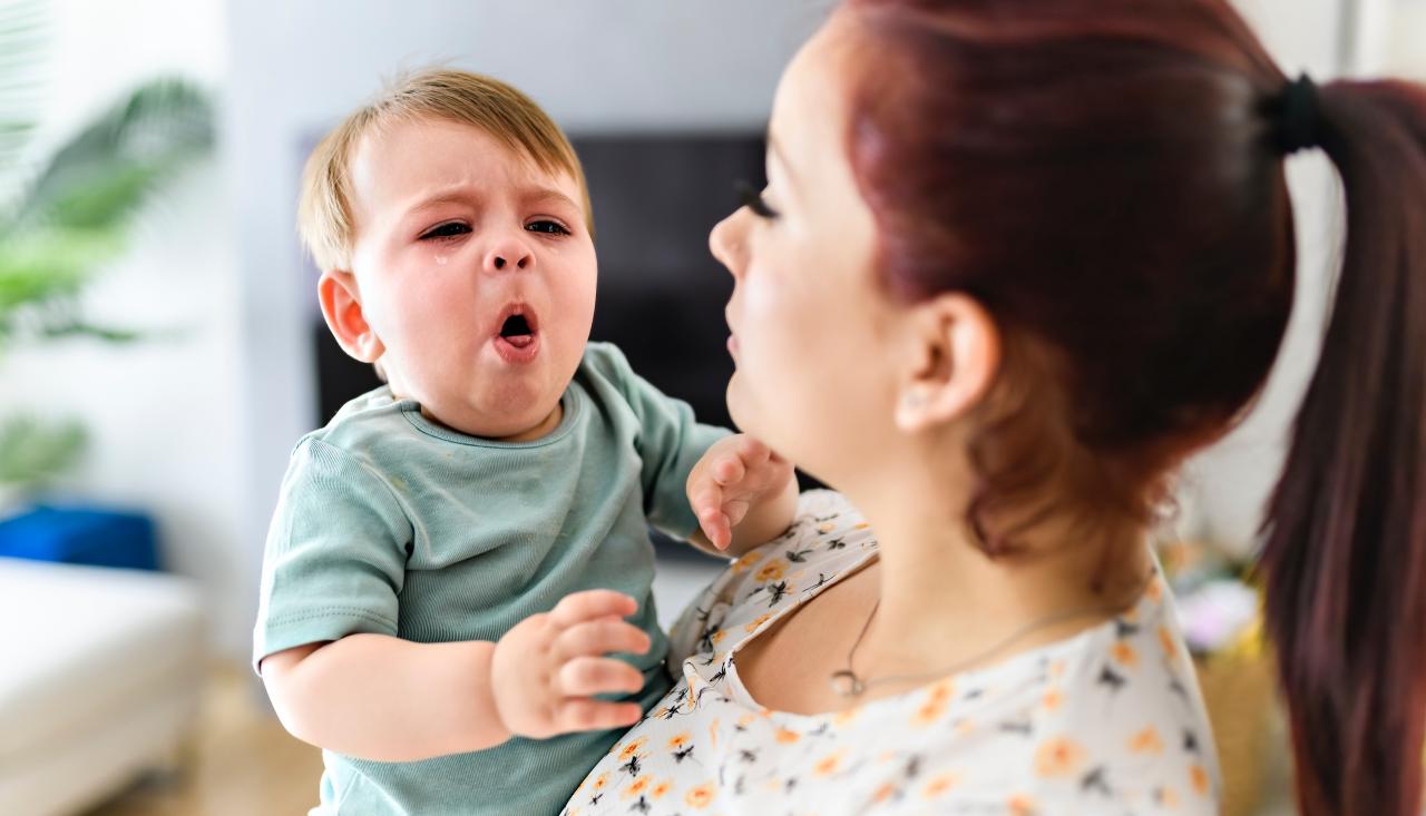 Mother holding a coughing baby