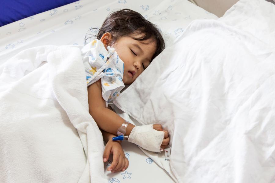 A sick child asleep on a hospital bed