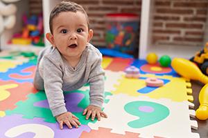 A baby crawling on the floor covered with a numbers puzzle