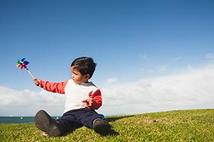 Boy sitting on grass playing with pinwheel