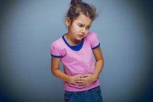 Young girl holding her tummy and looking like she's in discomfort 
