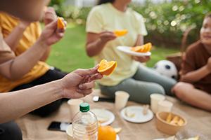 Family eating fresh ripe oranges at picnic in park