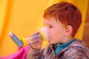 Image of child using an asthma inhaler with a spacer