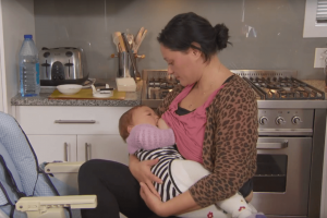 Mother breastfeeding her baby in the kitchen
